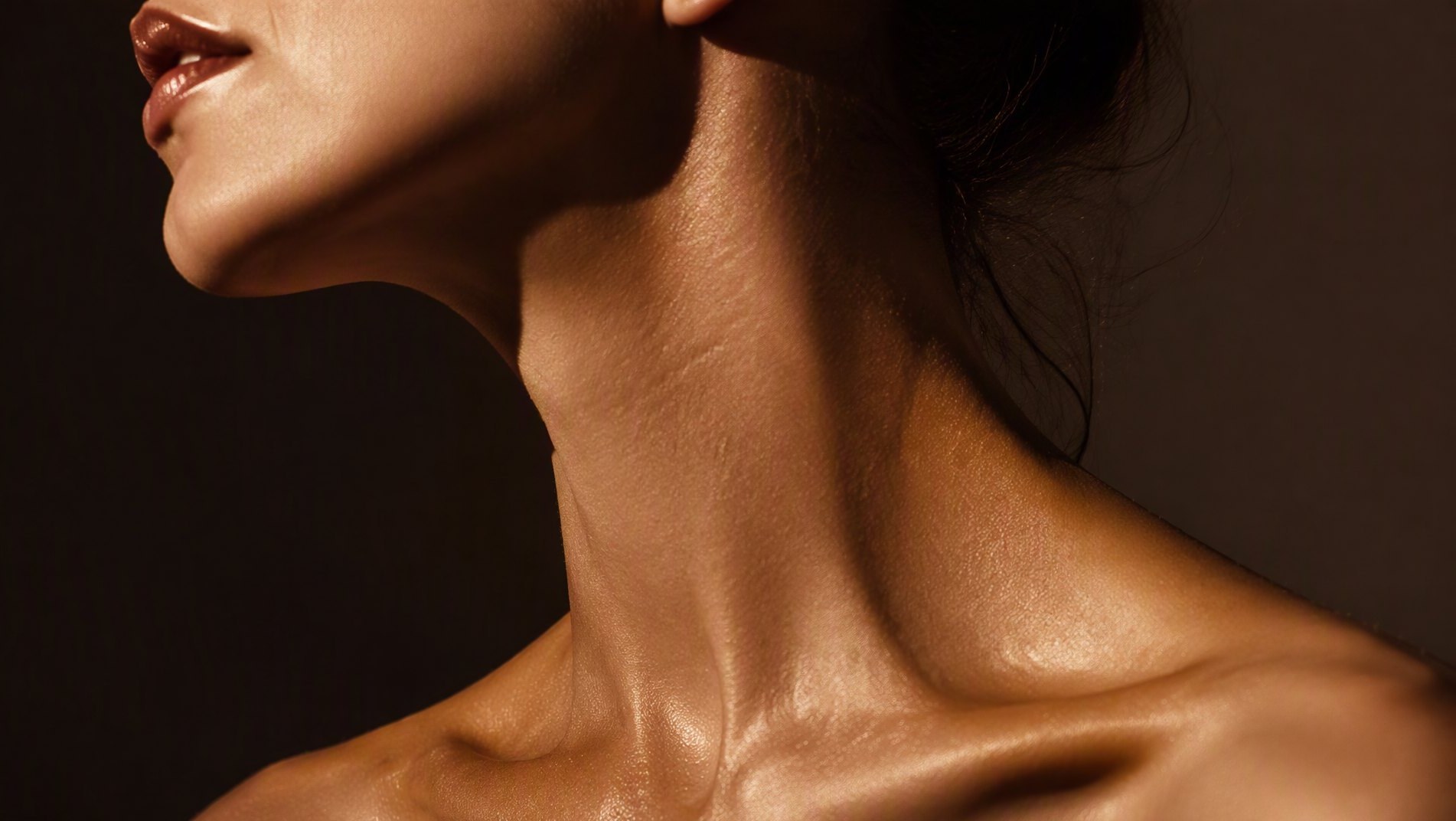 Macro study of a woman's jawline sculpted by warm light